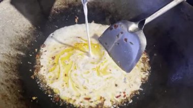 Asyalı aşçı Tayland mutfağında geleneksel köy usulü yemek pişiriyor. Tayland usulü yeşil köri ezmesi pişiriyor. Geleneksel tavada kızartılıyor.