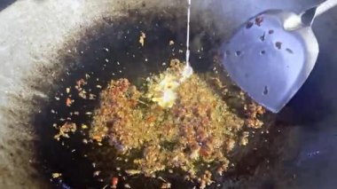 Asyalı aşçı Tayland mutfağında geleneksel köy usulü yemek pişiriyor. Tayland usulü yeşil köri ezmesi pişiriyor. Geleneksel tavada kızartılıyor.