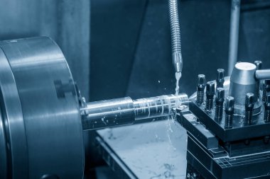 The lathe machine cutting the metal shaft parts with coolant method. The metalworking process by turning machine.