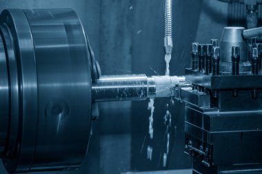 The lathe machine cutting the metal shaft parts with coolant method. The metalworking process by turning machine.