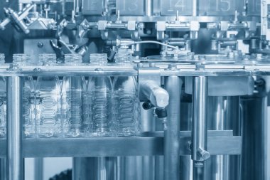 Taşıyıcı banttaki boş su şişelerini doldurmak için kapatın. İçme suyu üretim sürecinin yüksek teknolojisi.