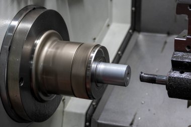 The  CNC lathe machine boring  cutting the metal shaft parts. The hi-technology metal working processing by CNC turning machine .