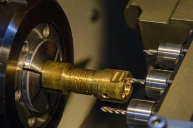The  multi tasking CNC lathe machine  drilling the brass shaft parts. The hi-technology metal working processing by CNC turning machine .