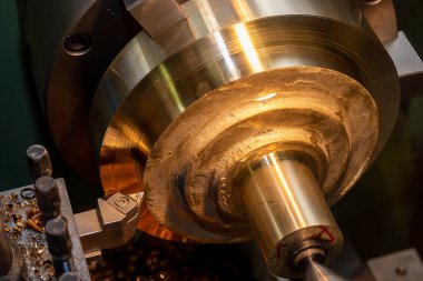 Torna makinesinin pirinç parçalarını kestiği yakın çekim sahnesi. Makineyi döndürerek metal işleme süreci.