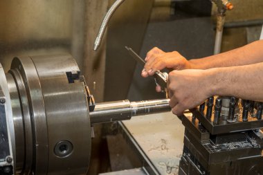 Görüntüyü kapatın. Makine operatörü Vernier Caliper 'ı çevirerek metal şaft parçalarını ölçüyor. Dönüş makinesinin kalite kontrolü. 