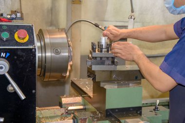 The machine operator working with lathe machine. The metalworking process by turning machine.