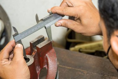 Sahneyi kapatın, makine operatörü Vernier Caliper 'ı çevirerek metal parçalarını ölçüyor. Dönüş makinesinin kalite kontrolü. 