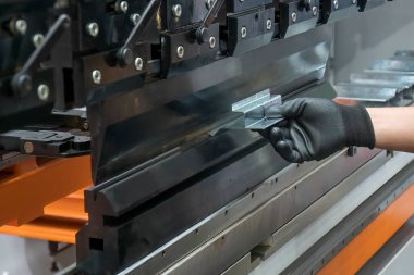 Bükme makinesini kapat. Metal parçaları tut ve lastik eldiveni tak. Yetenek operatörünün kullandığı levha metal çalışması.