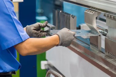 Bükme makinesini kapat. Metal parçaları tut ve güvenlik eldiveni tak. Yetenek operatörünün kullandığı levha metal çalışması.