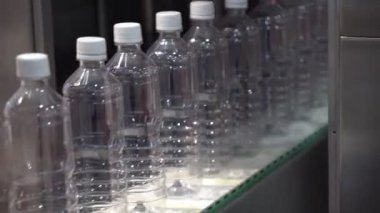 Taşıyıcı banttaki plastik şişe doldurma işlemi. İçme suyu şişesi üretim süreci.