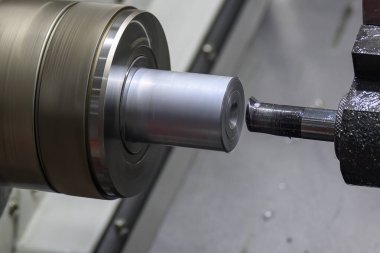 The  CNC lathe machine boring  cutting the metal shaft parts. The hi-technology metal working processing by CNC turning machine .