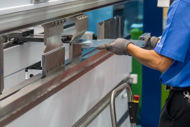 Bükme makinesini kapat. Metal parçaları tut ve güvenlik eldiveni tak. Yetenek operatörünün kullandığı levha metal çalışması.