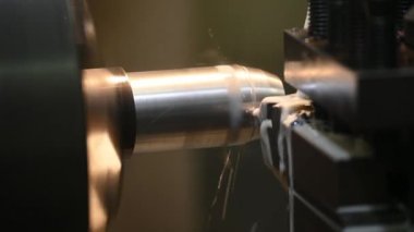Torna makinesi, metal şaft parçalarını sıvı soğutucuyla kesiyor. Makineyi döndürerek metal işleme süreci.