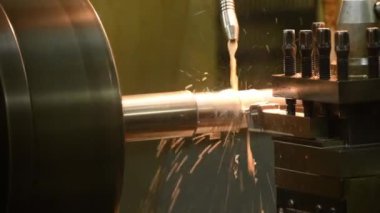 Kapanış sahnesinde torna makinesi soğutma metoduyla metal şaft parçalarını kesmiş. Makineyi döndürerek metal işleme süreci.