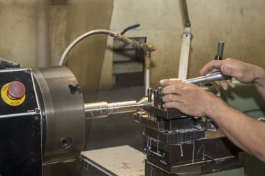 The machine operator working with lathe machine. The metalworking process by turning machine.