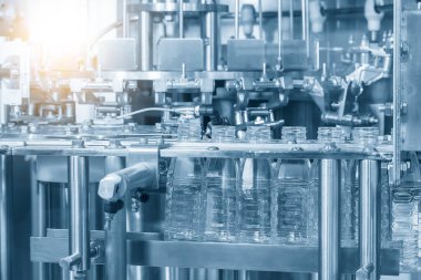 Taşıyıcı banttaki boş su şişelerini doldurmak için kapatın. İçme suyu üretim sürecinin yüksek teknolojisi.