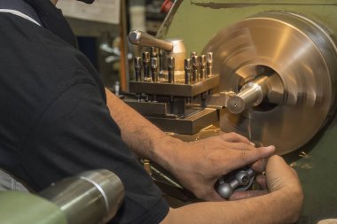 The machine operator working with lathe machine. The metalworking process by turning machine.