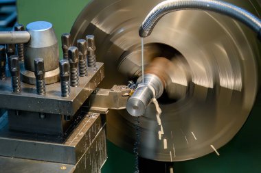 Torna makinesi metal şaft parçalarını sıvı soğutucu metoduyla kesiyor. Makineyi döndürerek metal işleme süreci.