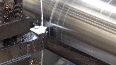 Torna makinesi, sıvı soğutucu metoduyla büyük metal gövde parçalarını kesiyor. Makineyi döndürerek metal işleme süreci.