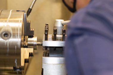 The machine operator working with lathe machine. The metalworking process by turning machine.
