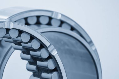 The cylindrical rolling bearing parts in light blue scene. The heavy mechanical part manufacturing concept.