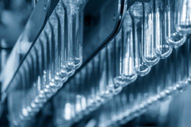 Tepedeki korkuluklara asılı bir grup preform şeklin yakın çekim sahnesi. Plastik şişe üretim süreci için hammadde.