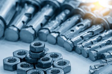 Açık mavi sahnede altıgen fındık parçaları yığını. Mekanik parçalar üretim süreci.