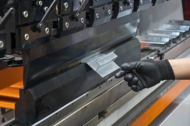Bükme makinesi operatörünü kapatın ve metal parçaları lastik eldivenle tutun. Yetenek operatörünün kullandığı levha metal çalışması.