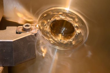 Closeup scene the lathe machine finish cut the brass parts by lathe tools. The metalworking process by turning machine.