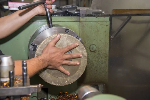 The machine operator working with lathe machine. The metalworking process by turning machine.