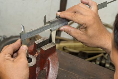 Sahneyi kapatın makine operatörü dökme demir parçalarının boyutunu Vernier Caliper 'a göre ölçüyor. Dönüş makinesinin kalite kontrolü. 