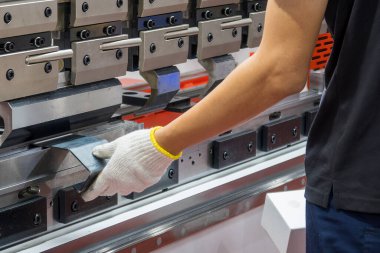 Bükme makinesi operatörünü kapatın ve metal parçaları güvenlik eldiveniyle tutun. Yetenek operatörünün kullandığı levha metal çalışması.