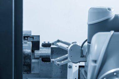 CNC torna makinesinin metal parçalarını tutan otomatik robot kolu. Dönüşüm makinesinde robotik sistem tarafından yüksek teknoloji materyal işleme süreci. 