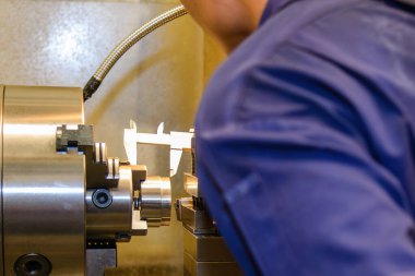 Sahneyi kapat, makine operatörü parçaları Vernier Caliper 'a göre döndürme boyutunu ölçüyor. Dönüş makinesinin kalite kontrolü. 