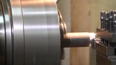 Torna makinesinin metal şaft parçalarını sıvı soğutucu metoduyla kestiği sahne. Makineyi döndürerek metal işleme süreci.