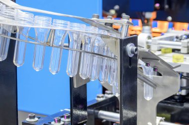 Taşıyıcı bant, önceden şekillendirilmiş şekli üfleme makinesine teslim eder. Plastik şişe üfleme makinesi operasyonu..
