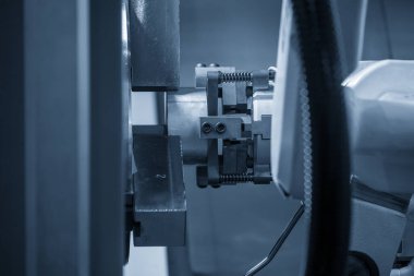 CNC torna makinesinin metal parçalarını tutan otomatik robot kolu. Dönüşüm makinesinde robotik sistem tarafından yüksek teknoloji materyal işleme süreci. 