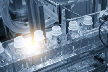 Taşıyıcı banttaki boş içme suyu şişeleri doldurmak için. İçme suyu üretim sürecinin yüksek teknolojisi. 