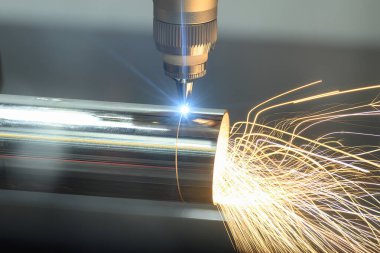 Sahneyi kapatın, fiber lazer kesme makinesi paslanmaz çelik tüpü parlak ışıkla kesti. Lazer kesme makinesinin yüksek teknoloji metal üretim süreci.. 