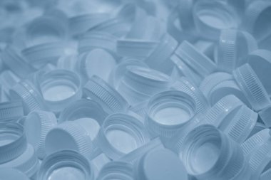Plastik şişe kapakları açık mavi sahnede. PET şişe üretim süreci kavramları.