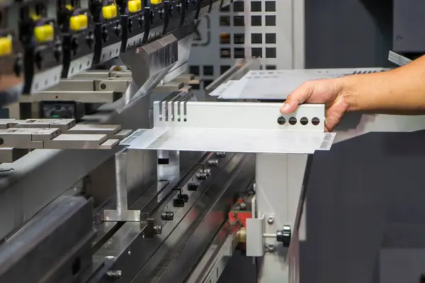 stock image Close up the bending machine operator hold the sheet metal parts. The sheet metal working operation by skill operator.