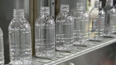 Yavaş çekim sahnesi doldurmak için taşıyıcı banttaki boş su şişeleri. İçme suyu üretim sürecinin yüksek teknolojisi. 