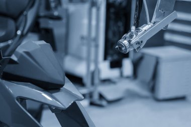Açık mavi sahnede motorsiklet parçalarıyla çalışan otomatik boyama robotu sahneyi kapatın. Otomotiv fabrikasındaki yüksek teknolojili tablo..