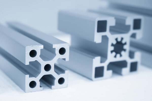 Close up scene the sample parts of aluminum profile extrusion manufacturing concept in the light blue scene. The various type of square  shape of aluminum profile. 