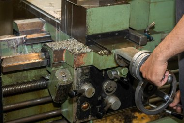 The machine operator working with lathe machine. The metalworking process by turning machine.