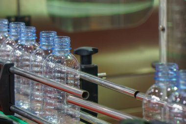 İçme suyu imalatının yüksek teknoloji materyali. Taşıma bandındaki boş içme suyu şişelerini doldurmak için.. 