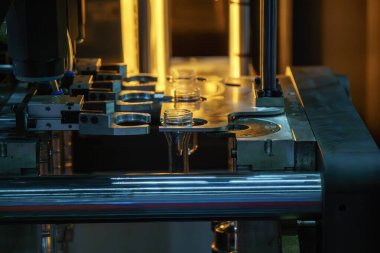 Taşıyıcı bant, önceden şekillendirilmiş şekli üfleme makinesine teslim eder. Plastik şişe üfleme makinesi operasyonu..