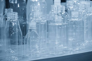 Açık mavi sahnedeki çeşitli plastik şişe kutuları. İçme suyu üretim sürecinin yüksek teknolojisi..