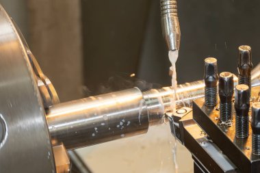 Torna makinesi metal şaft parçalarını sıvı soğutucu metoduyla kesiyor. Makineyi döndürerek metal işleme süreci.