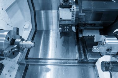 Açık mavi sahnedeki çift taret CNC torna makinesi. CNC dönüşüm makinesinin yüksek teknoloji metal çalışma süreci.